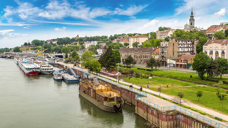 Åk på båttur på floden Donau och Sava på en resa till Belgrad med grön natur och hus.